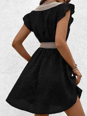 Black chevron textured mini dress with V-neck, short sleeves, and decorative belt.