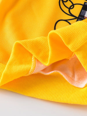 Yellow baby hoodie detail with bear graphic and plaid accents.