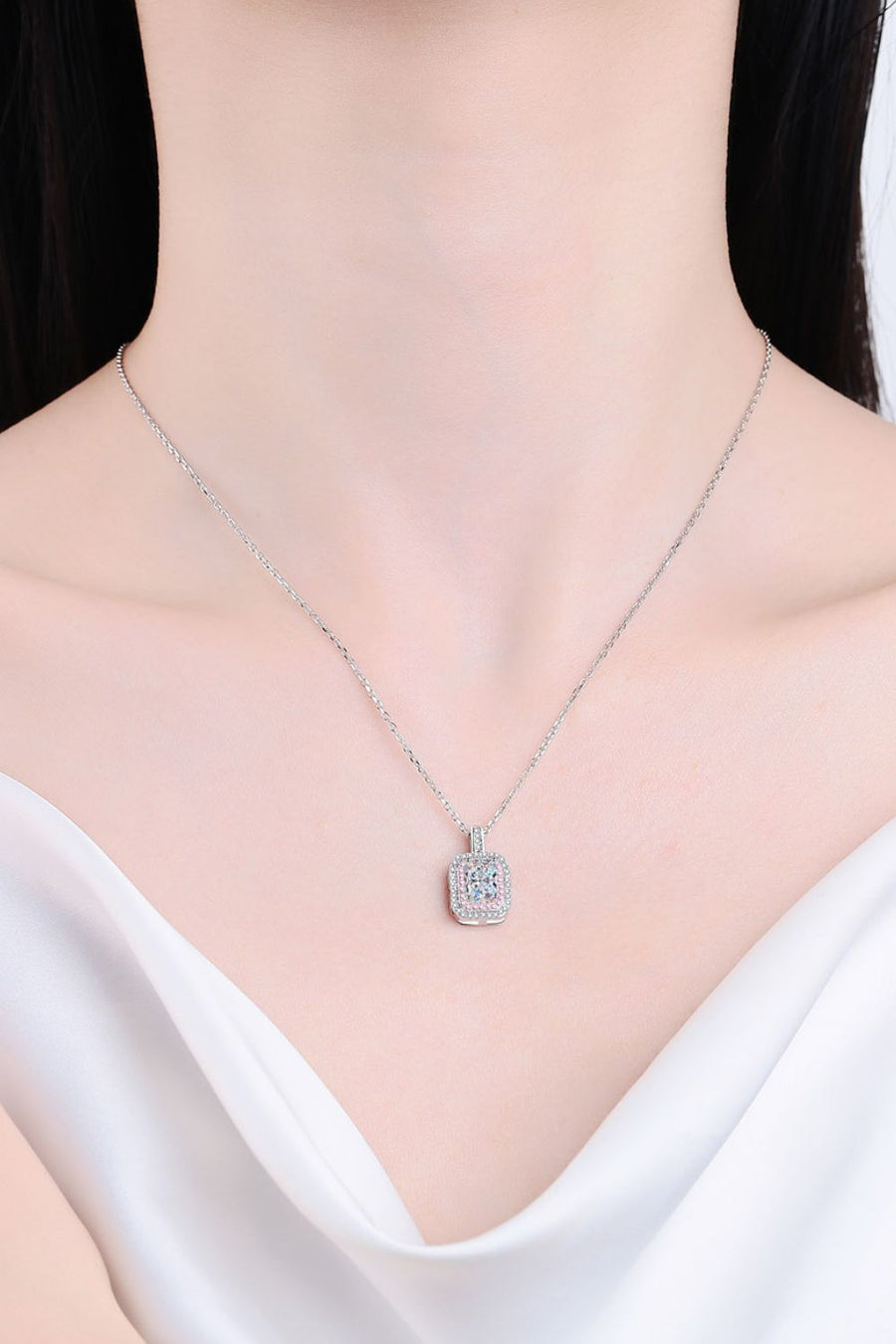 Silver moissanite halo necklace with a radiant cut center stone on a delicate chain.
