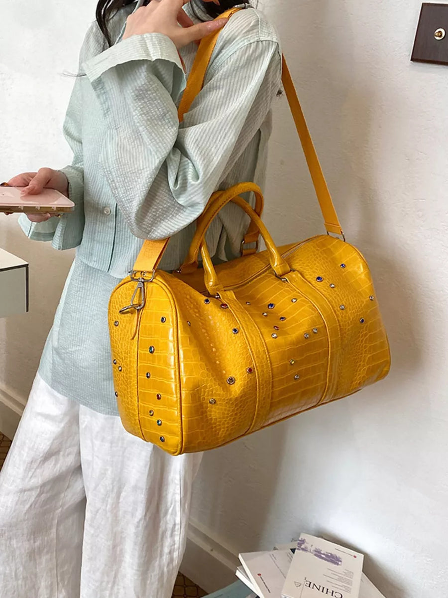 Yellow crocodile textured duffel bag with studded details and detachable strap