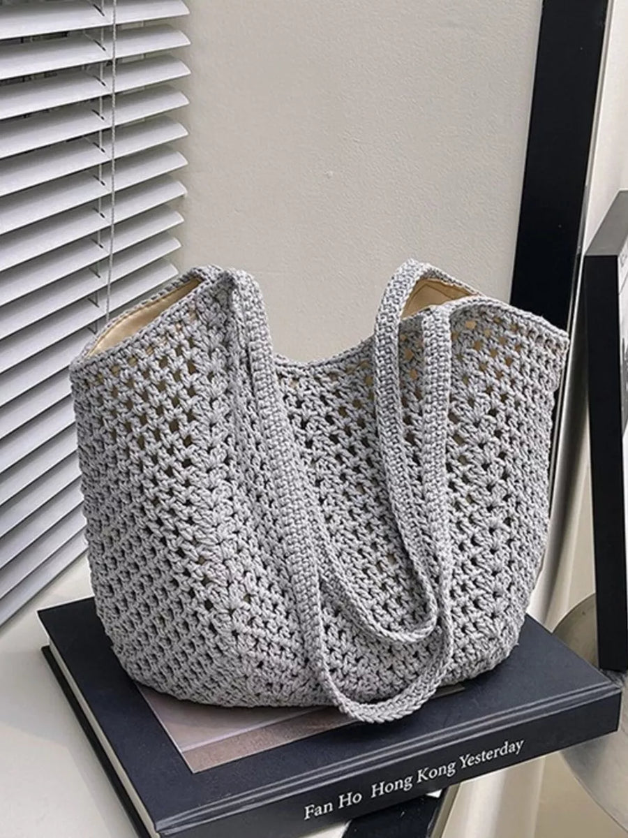 Grey woven straw shoulder bag with crochet detail and braided straps.