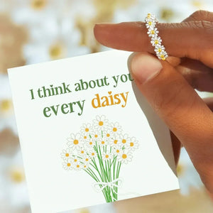 Silver daisy chain ring with yellow centers on a card that says "I think about you every daisy