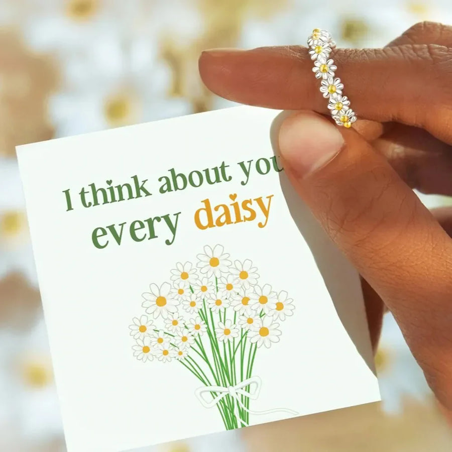 Silver daisy chain ring with yellow centers on a card that says "I think about you every daisy