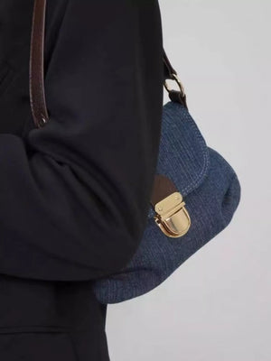 Mini denim shoulder bag in blue with a gold clasp and brown strap detail.