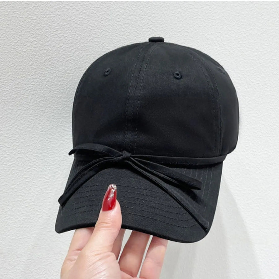 Black baseball cap with a bow detail and acrylic material.