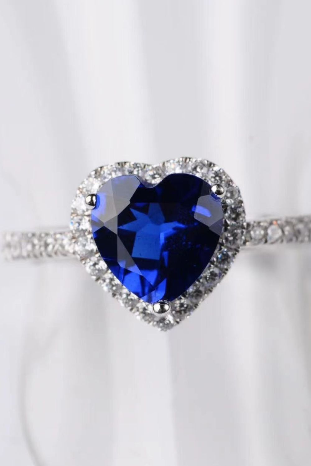 Blue heart halo engagement ring with clear accent stones on band