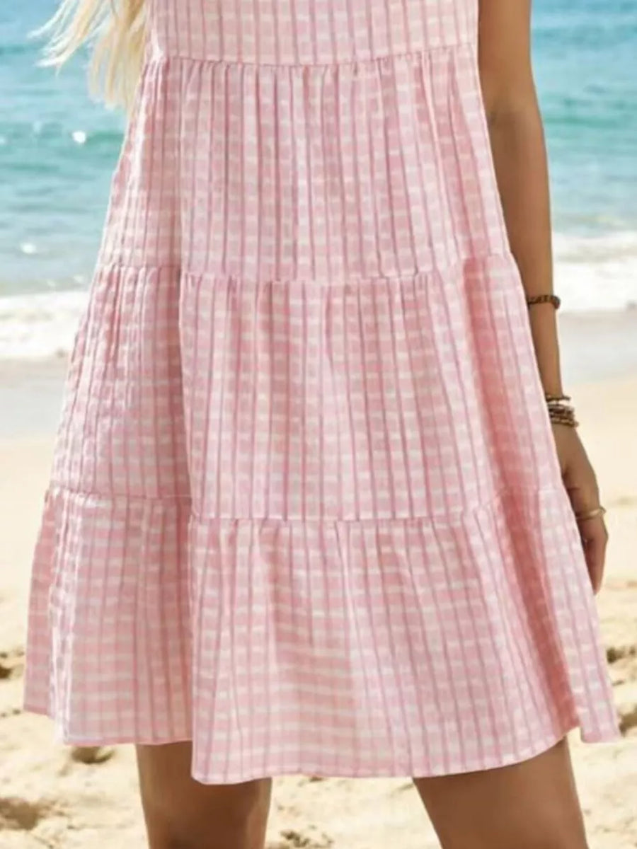 Pink tiered mini dress with a subtle checkered texture and a ruffled hem.