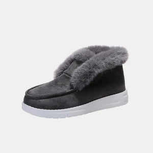 Dark gray suede slip-on booties with fluffy shearling trim and white sole.