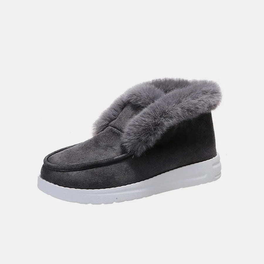 Dark gray suede slip-on booties with fluffy shearling trim and white sole.