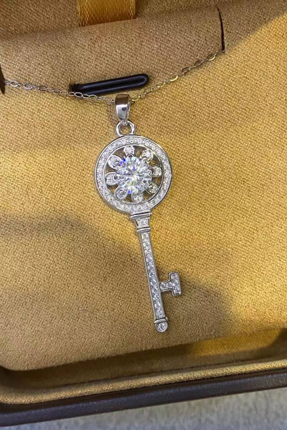 Silver floral key pendant necklace with clear crystals and a large center stone.