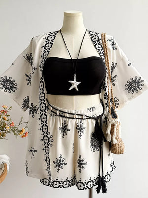 White polyester shorts and open cardigan set with black embroidered pattern and tassel belt.