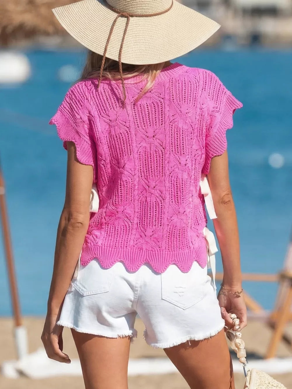 Chic openwork knit sweater vest in pink with cable knit pattern and adjustable side ties.