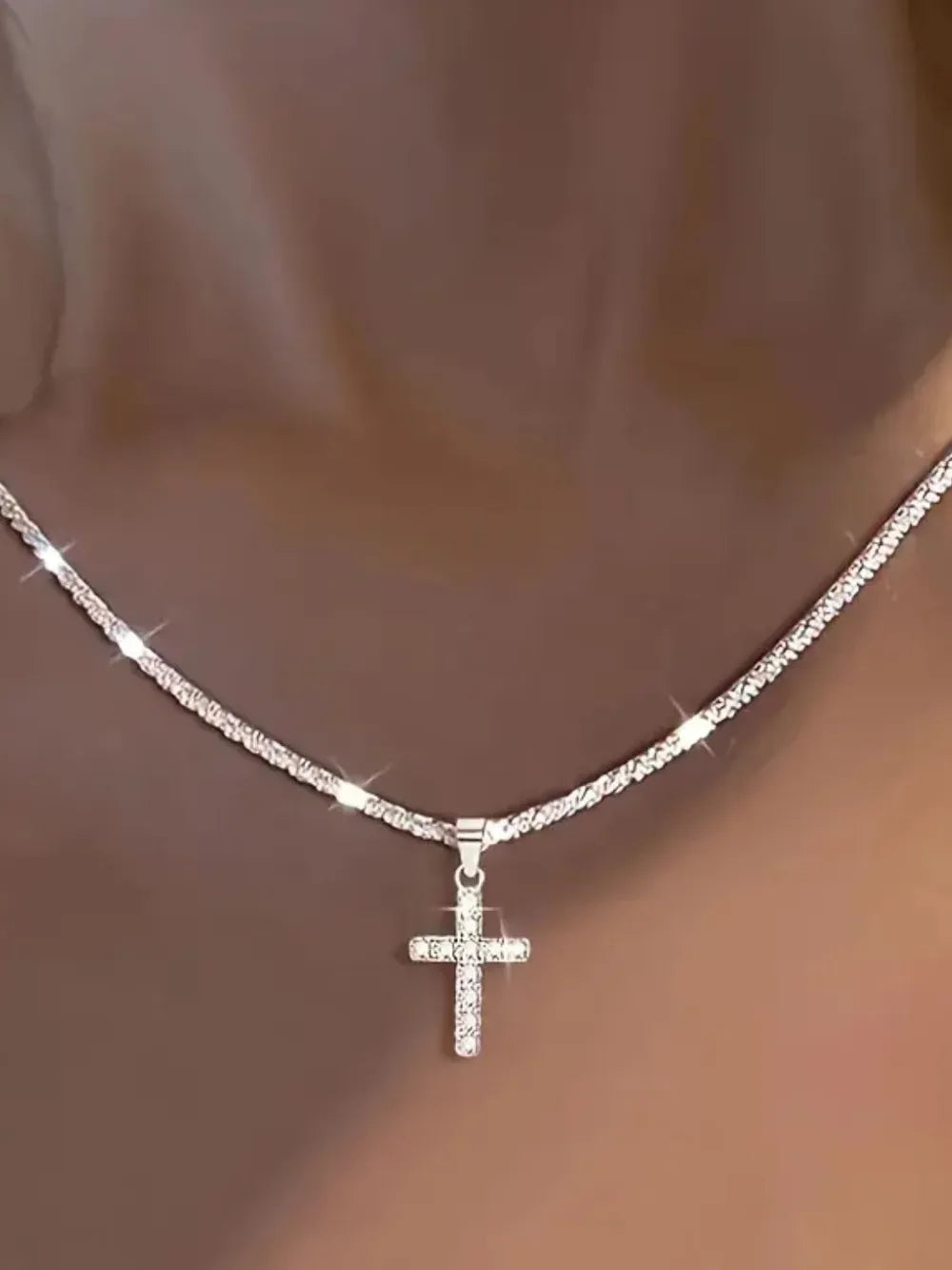 Sparkling silver cross pendant necklace with pave crystal detail on a textured chain.
