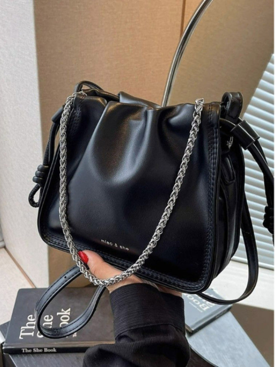 Black ruched PU leather crossbody bag with silver chain detail and knotted strap accents.