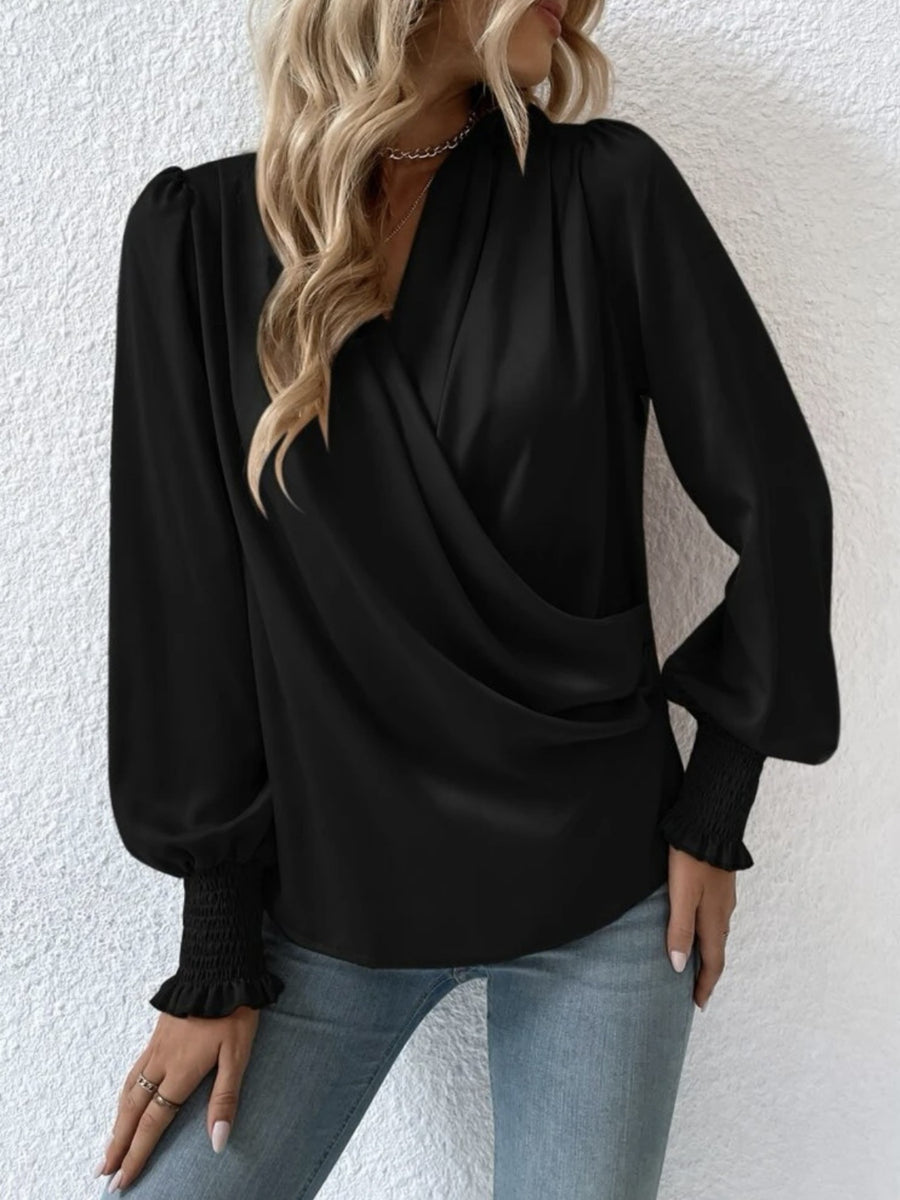 Black ruched surplice blouse with long puff sleeves and smocked cuffs.