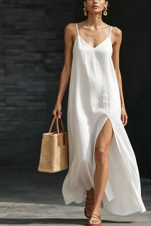 White V-neck maxi dress with spaghetti straps and a high slit, styled with a straw tote bag.