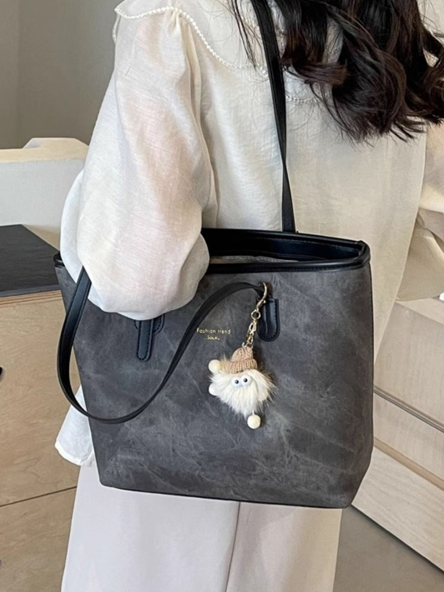Distressed dark gray pu leather tote bag with fuzzy charm and buckle accents.