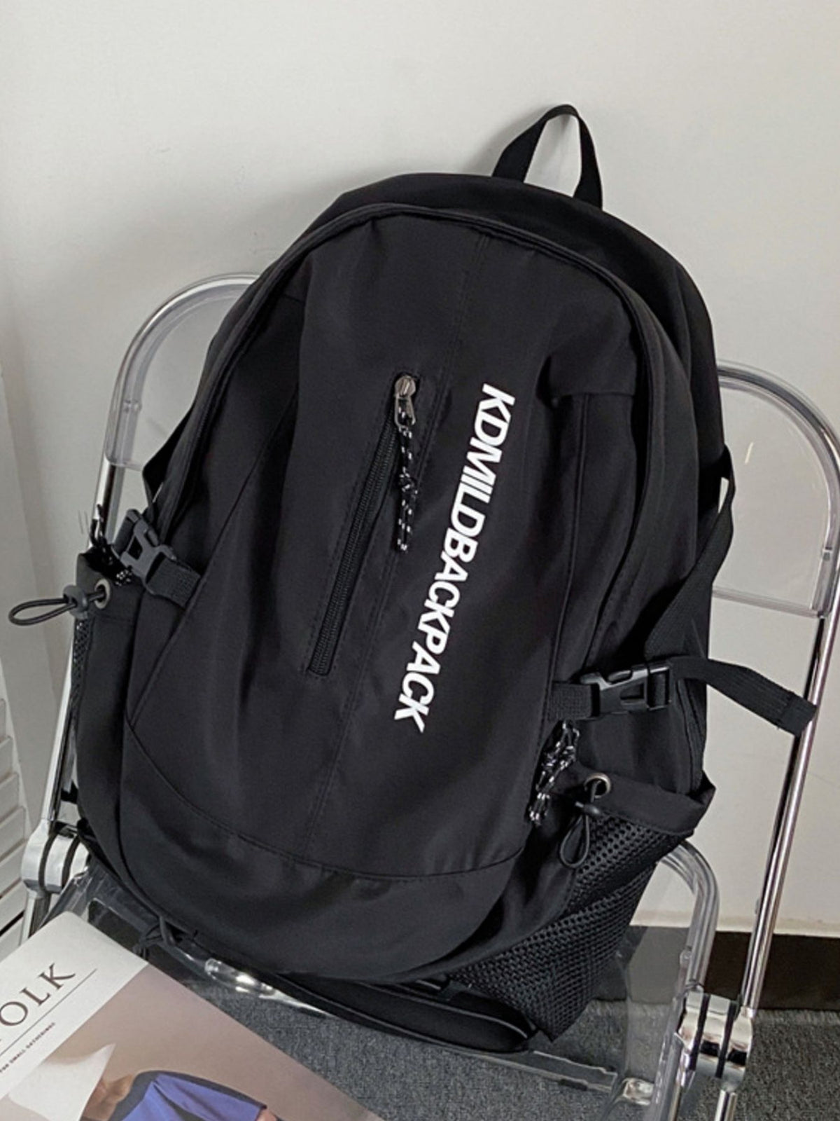 Black nylon casual backpack with white text and zippered pocket.