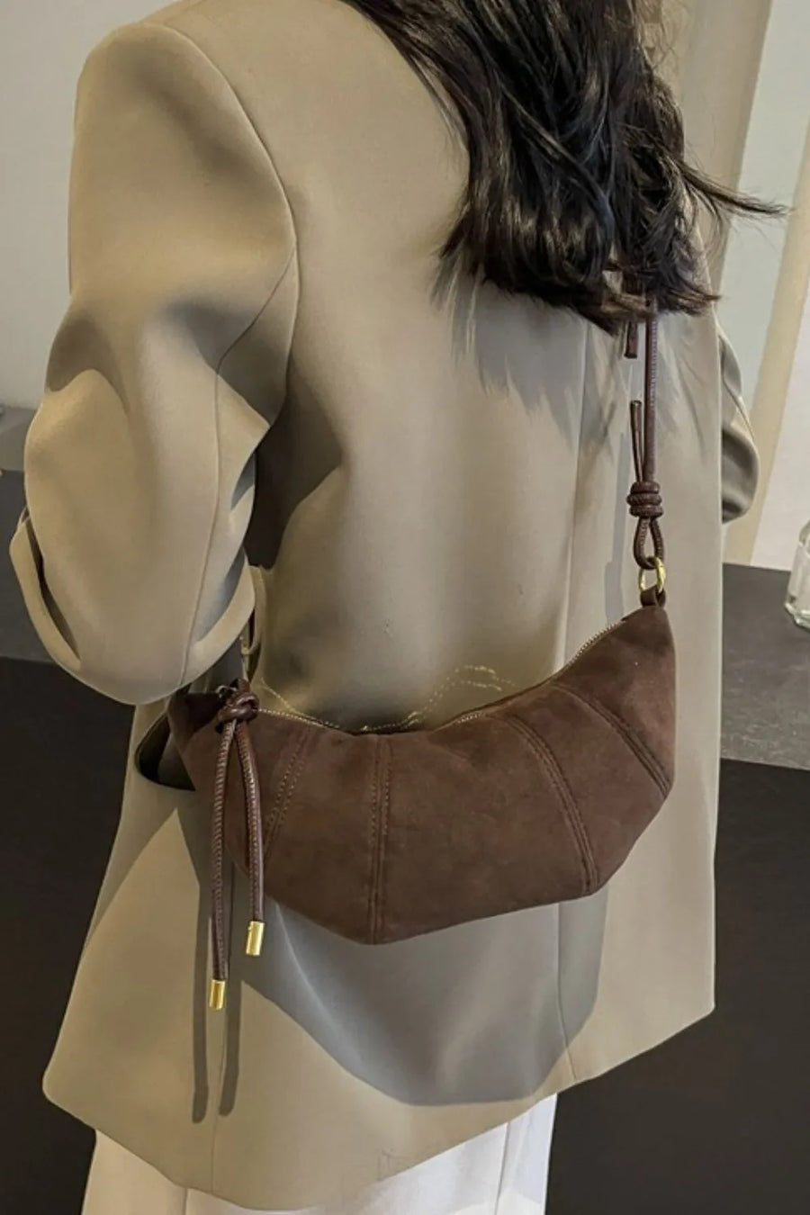 Brown suede crescent shoulder bag with knot detail and gold hardware
