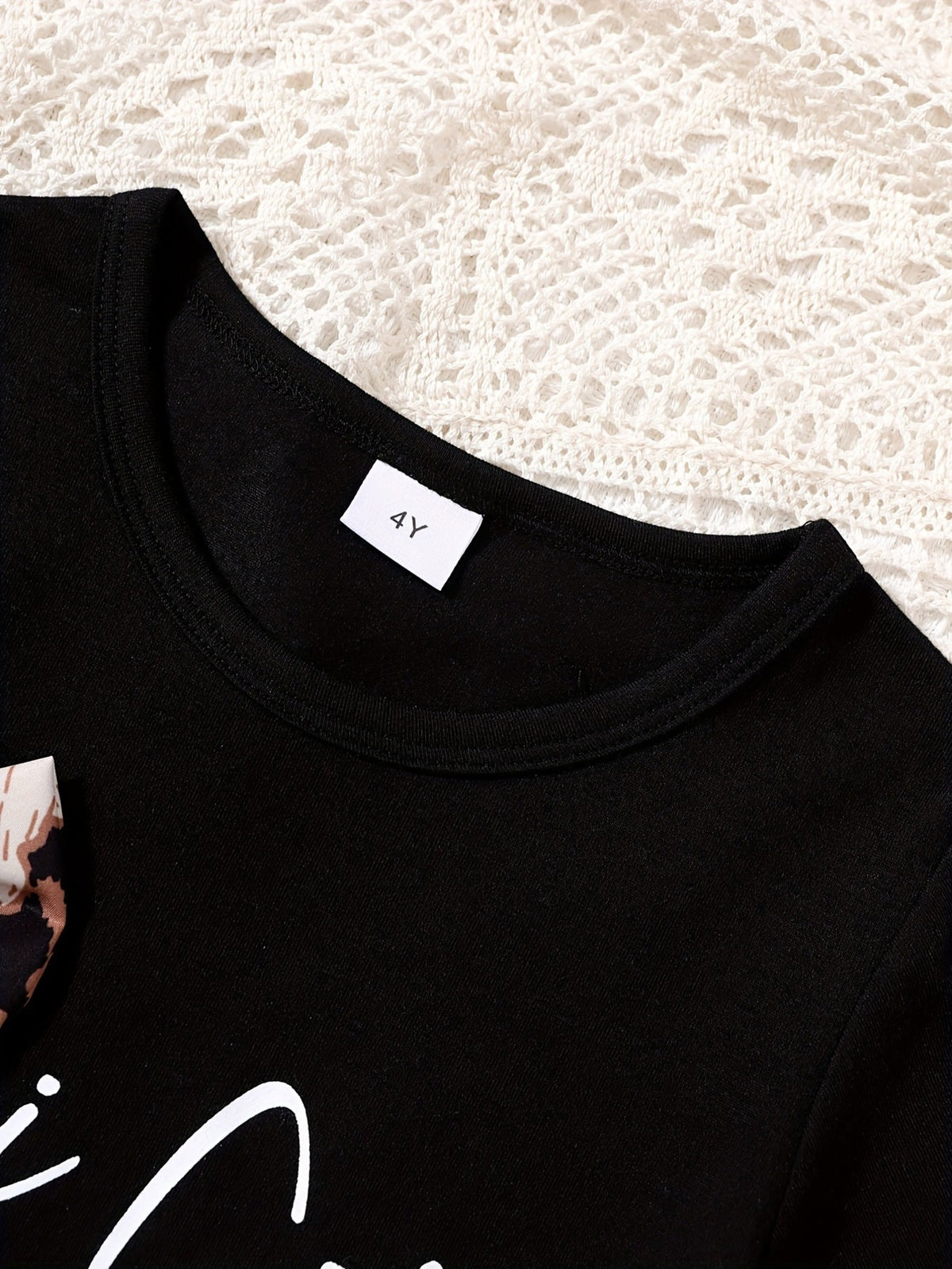 Black baby tee with leopard bow accent and white graphic print.