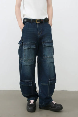 Layered pocket denim cargo trousers in dark blue with multiple functional pockets and a relaxed fit.