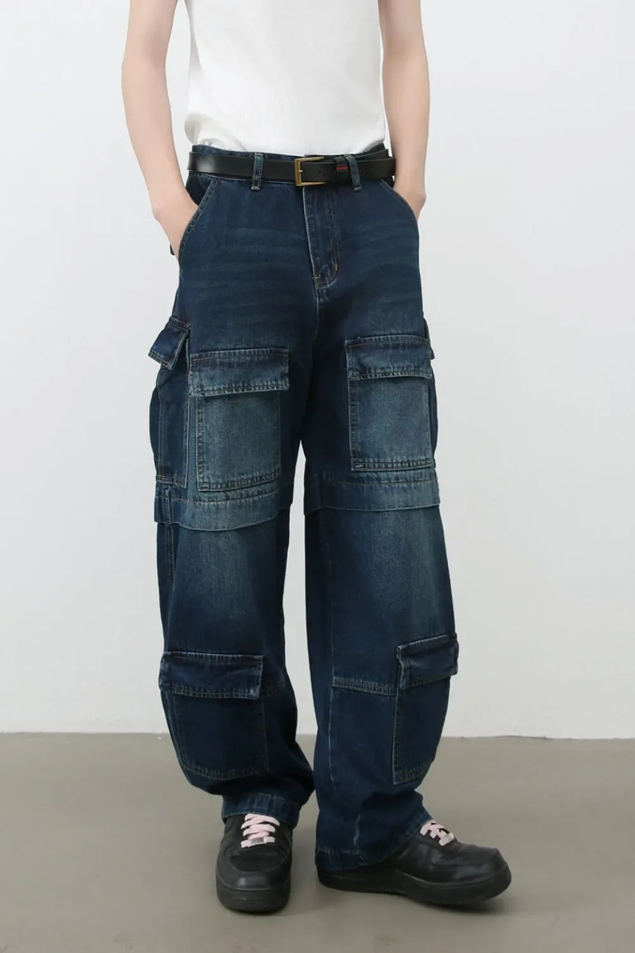 Layered pocket denim cargo trousers in dark blue with multiple functional pockets and a relaxed fit.