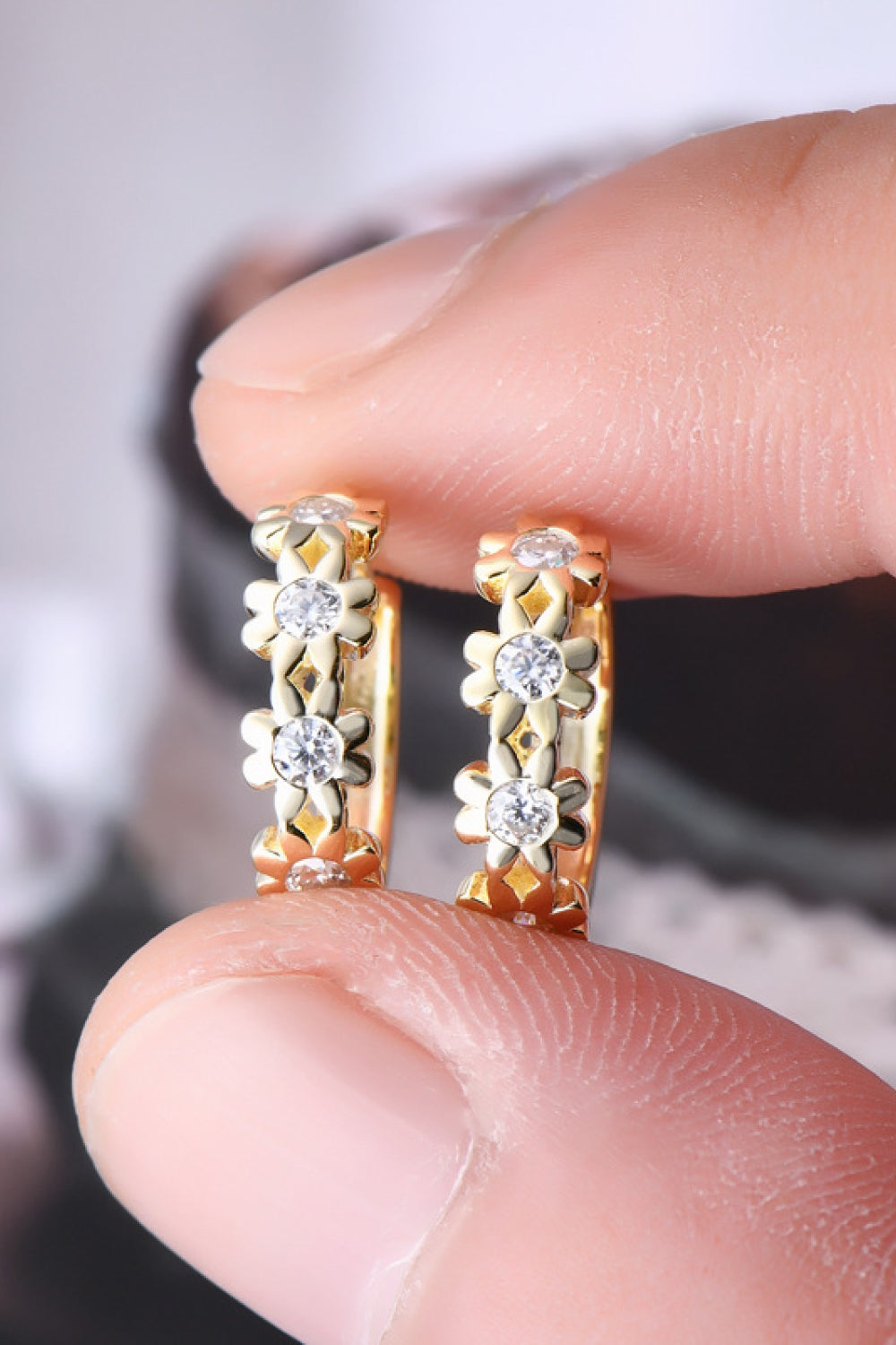 Gold huggie hoop earrings with floral embellishments and clear stones