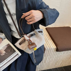 Elegant mini tote bag in light gray suede and brown leather with charm detail