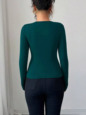 Teal long-sleeve tee with asymmetrical cutout detail, fitted silhouette.