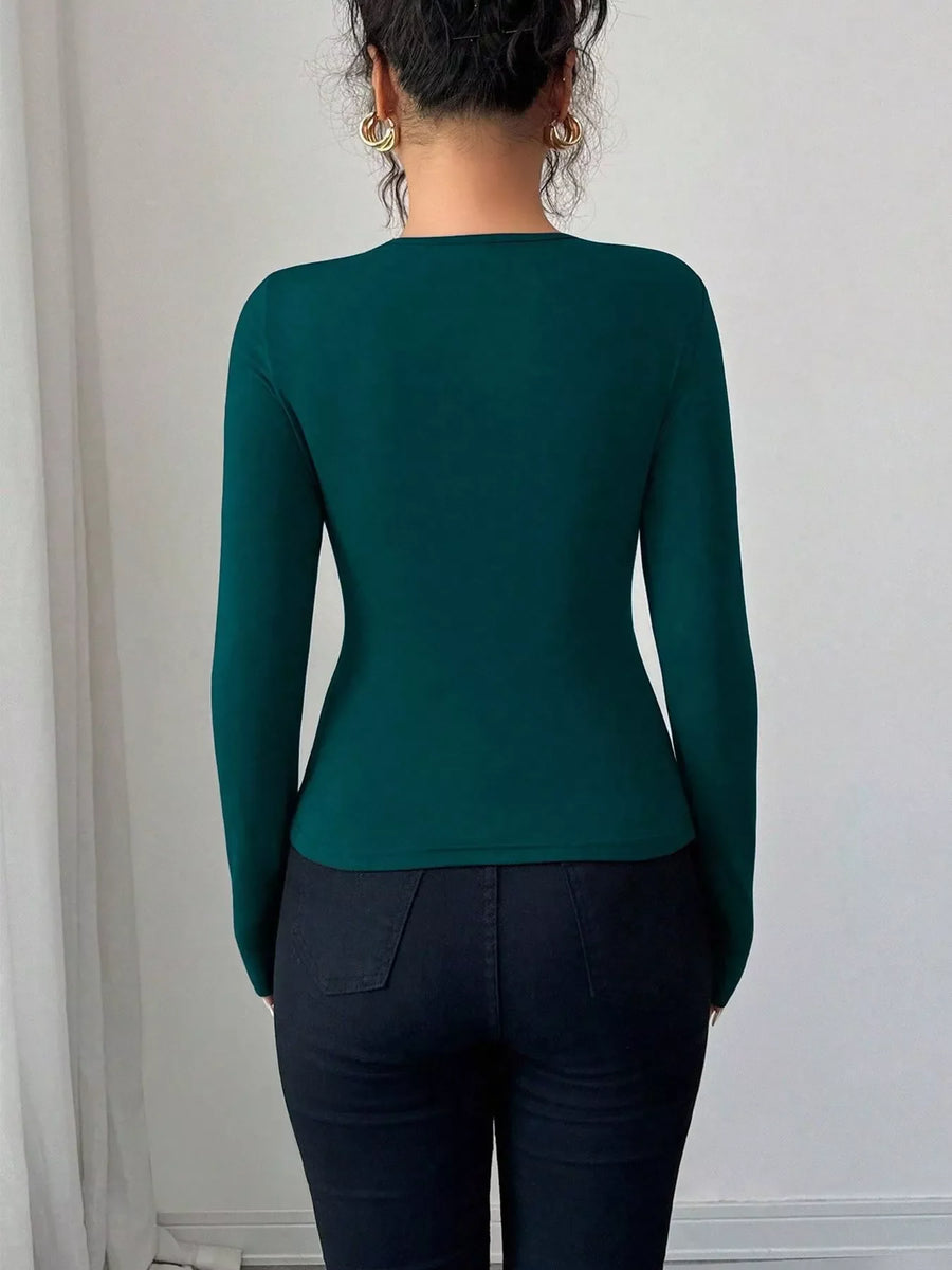 Teal long-sleeve tee with asymmetrical cutout detail, fitted silhouette.