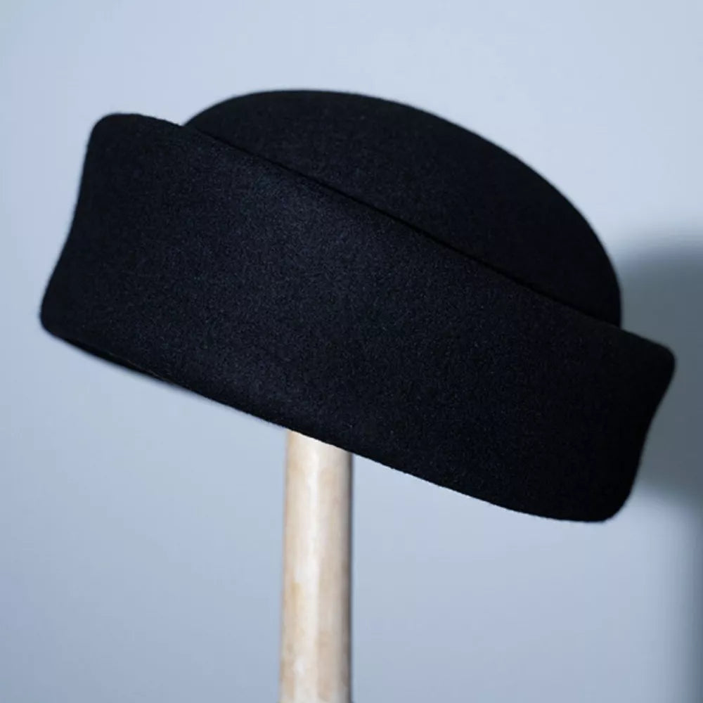 Black wool pillbox hat with a folded brim detail.