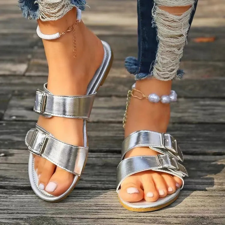 Silver metallic buckle slide sandals with double straps and adjustable buckles.
