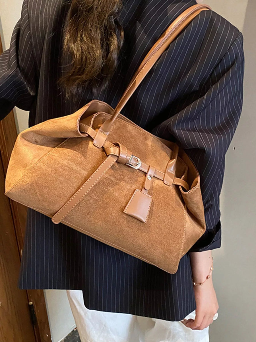 Women's chic brown suede shoulder bag with buckle detail and leather strap.