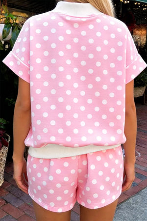 Pink polka dot top and shorts set with white trim, short sleeves, and cuffed hem.