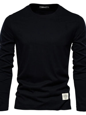 Black crew-neck long-sleeve tee with a textured patch detail on the hem.