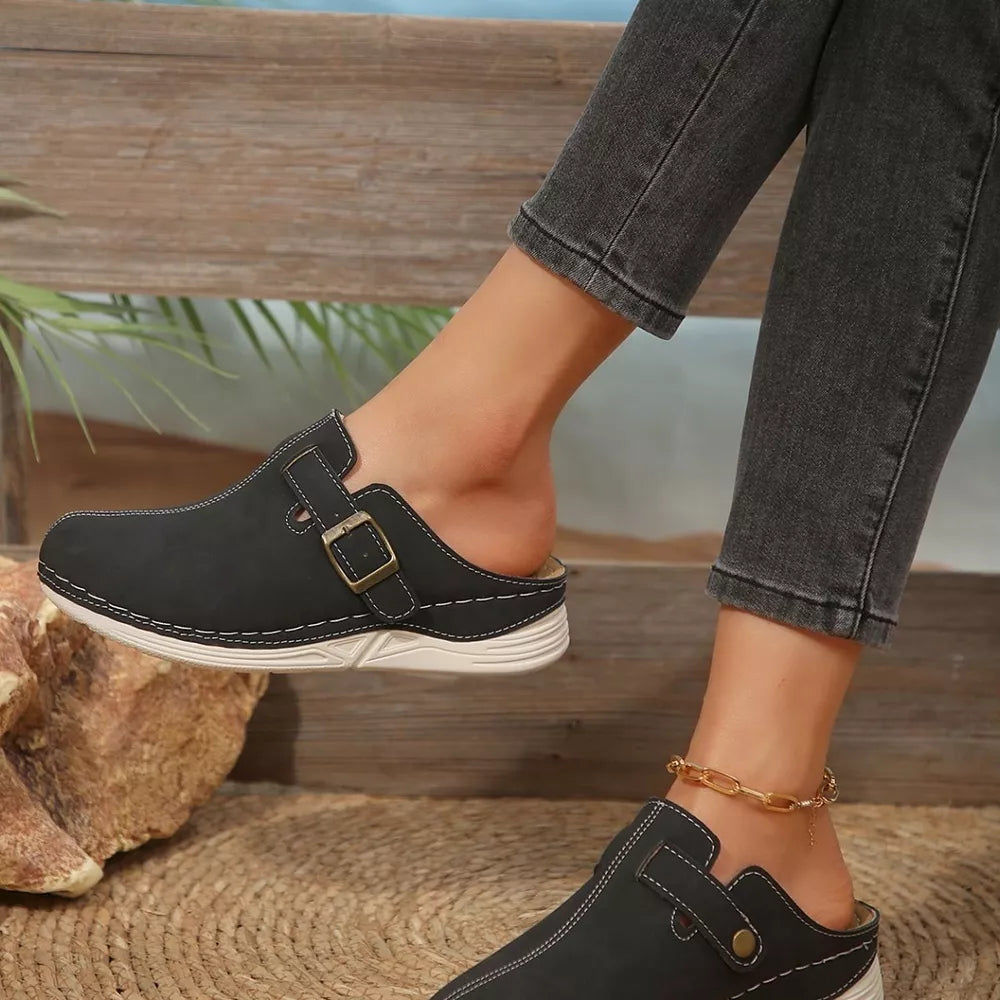 Black slip-on flats with buckle detail and contrast stitching.