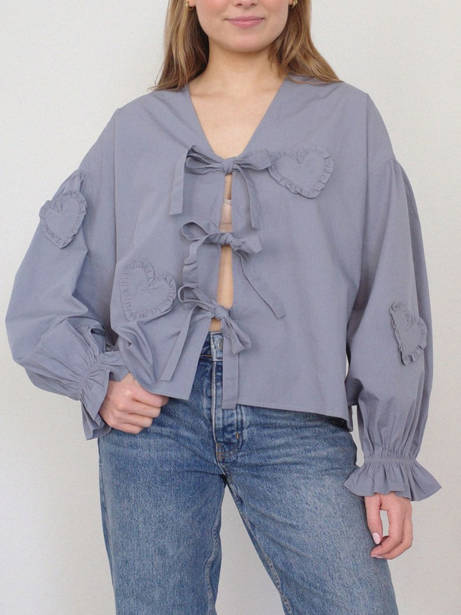 Lavender blouse with heart appliques and tie front, featuring ruffled cuffs and balloon sleeves.