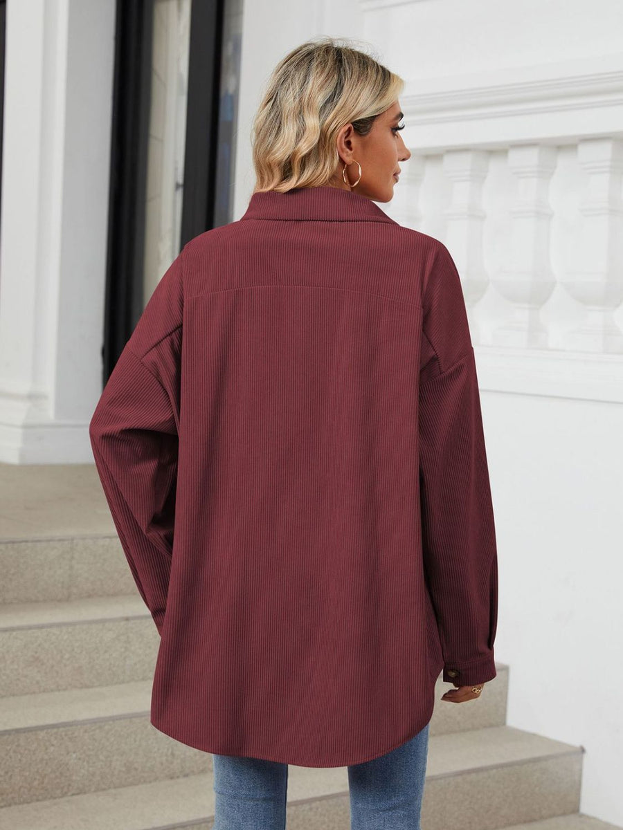 Oversized corduroy shirt jacket in burgundy with buttoned cuffs and a relaxed fit.