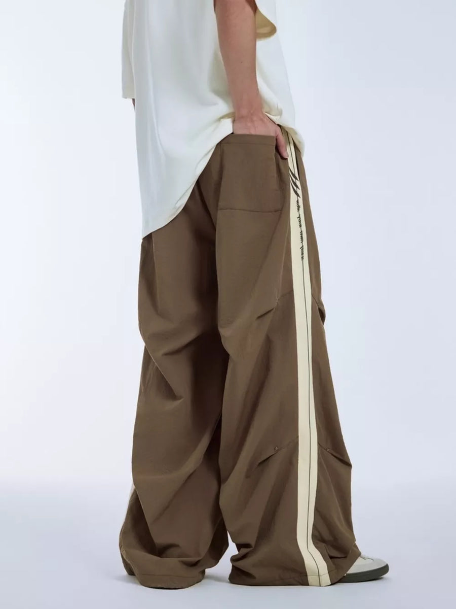 Brown relaxed fit sweatpants with cream side stripe and drawstring detail.