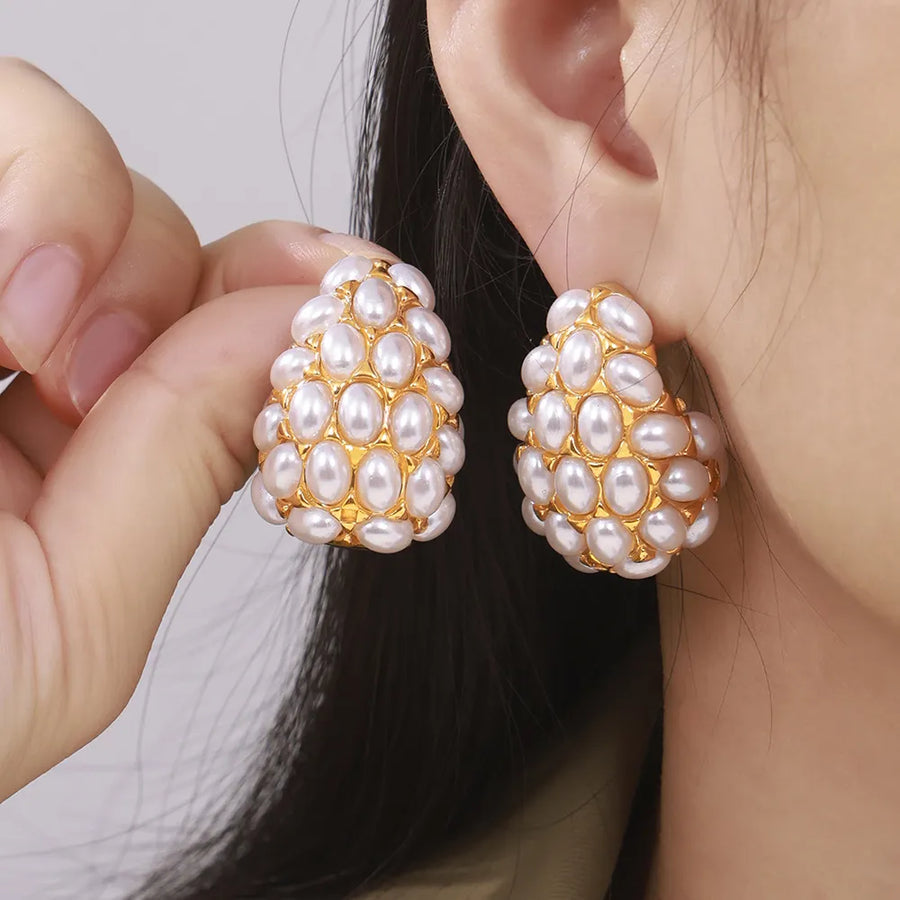 Gold sculptural earrings with clustered white pearls, a statement jewelry piece.