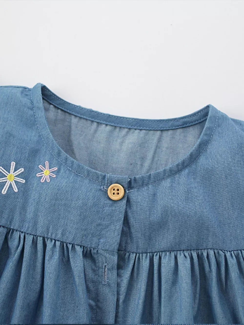 Denim dress with floral embroidery and wooden button front detail.