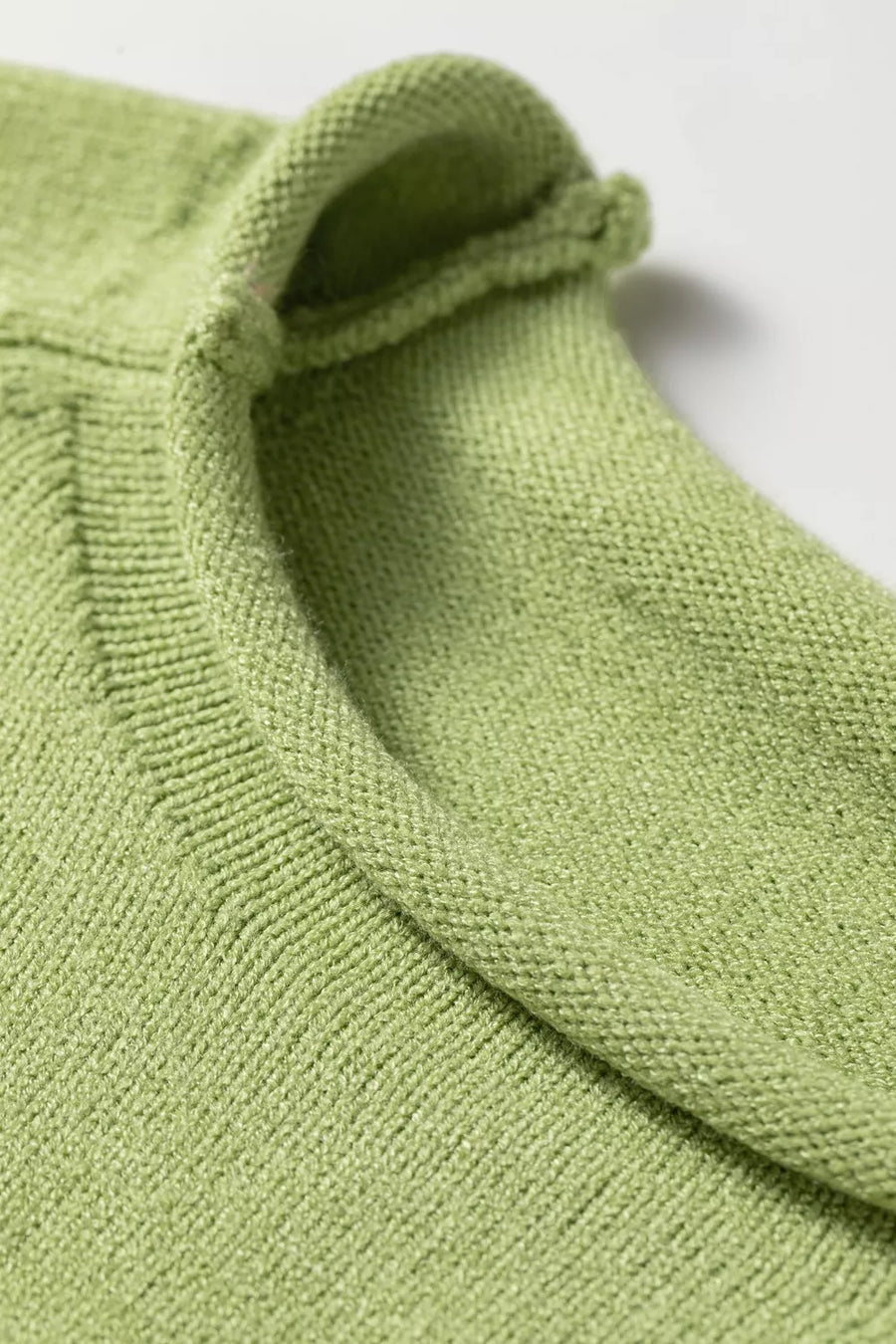 Light green knit sweater with a rolled collar and textured stitch detail.