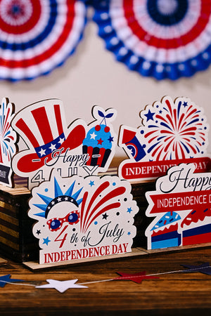 Patriotic wooden tabletop decor with USA flag hat, cupcake, fireworks, and Independence Day messages.
