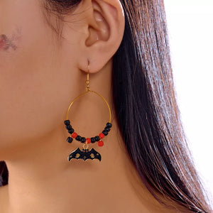 red earrings featuring bat charm and geometric