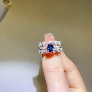 Sapphire and moissanite trio ring set in silver with blue oval center stone and diamond accents.