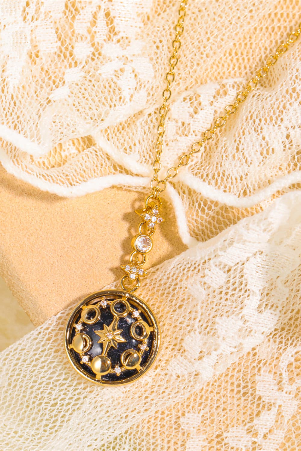 Gold celestial medallion pendant necklace with moon phases and stars, on a delicate chain.