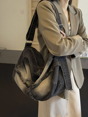 Frayed dark denim slouch crossbody bag with adjustable strap.