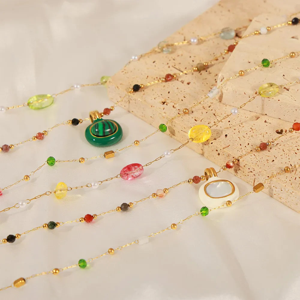 Gemstone cascade layered necklace with gold chain, featuring colorful beads and pendants in green, white, and red.