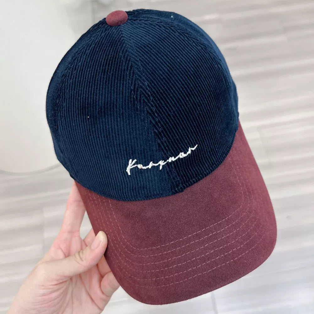 Two-tone corduroy baseball cap in navy blue and burgundy with white embroidered text.