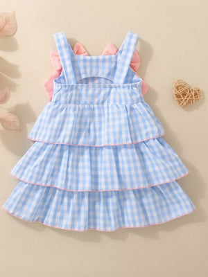 Blue gingham baby dress with tiered ruffles and pink bow accents on back.